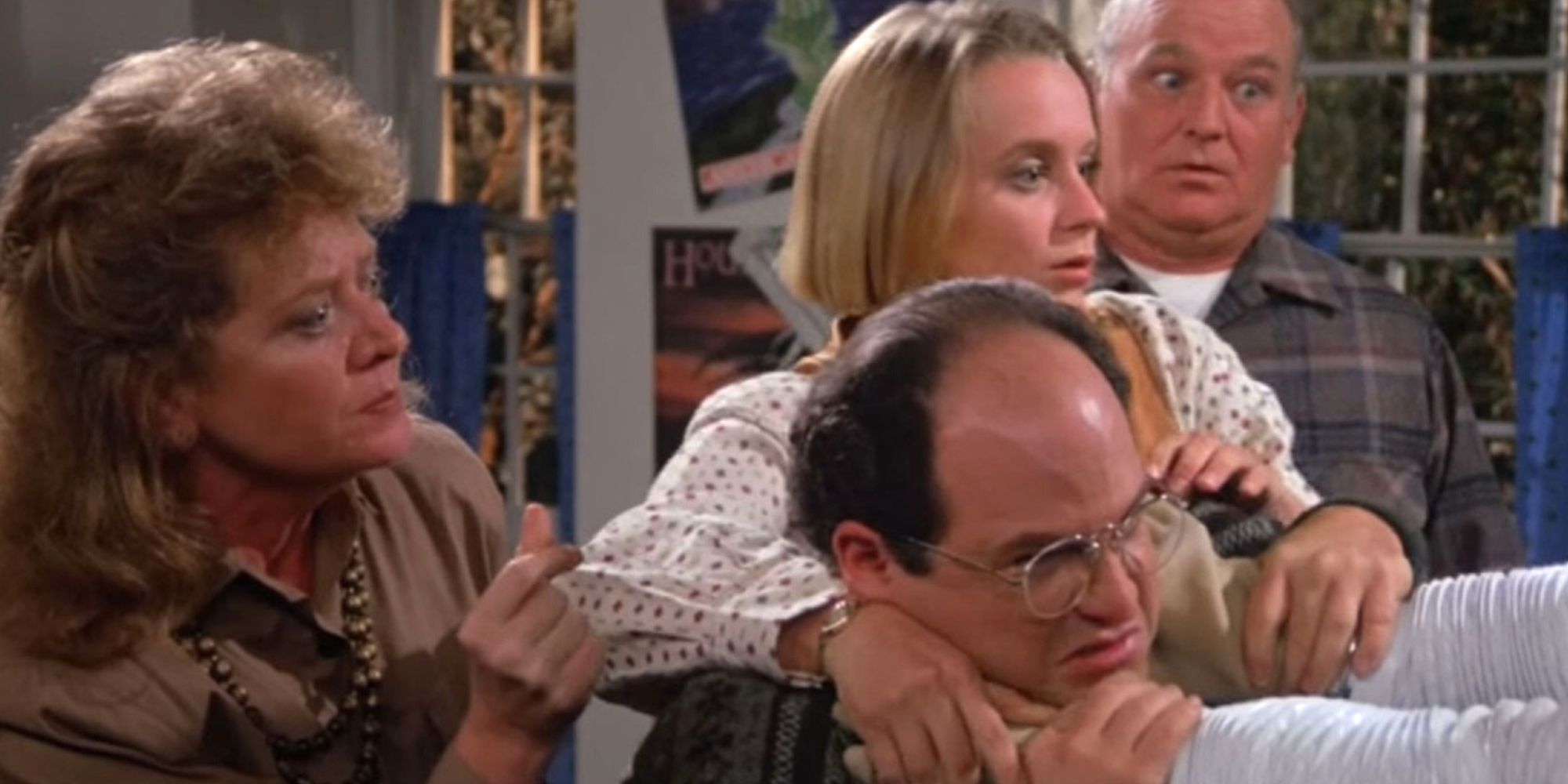 Um homem e duas mulheres seguram Jason Alexander, morto por Bubble Boy em Seinfeld