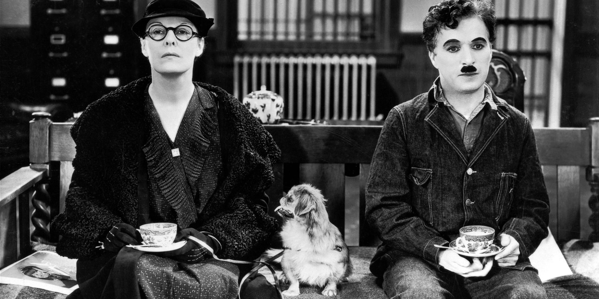 Charlie Chaplin as the Little Tramp sitting next to a woman in 'Modern Times'