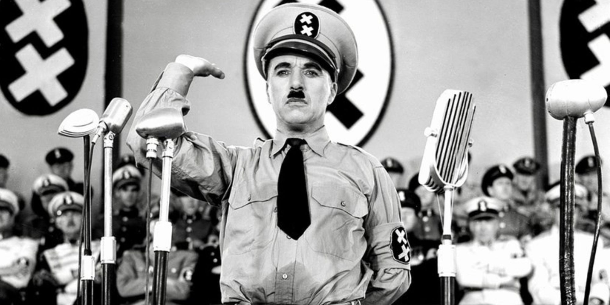 كان تشارلي شابلن يرتدي زي أدولف هتلر وهو يرفع ذراعه ويقف على منصة في فيلم The Great Dictator