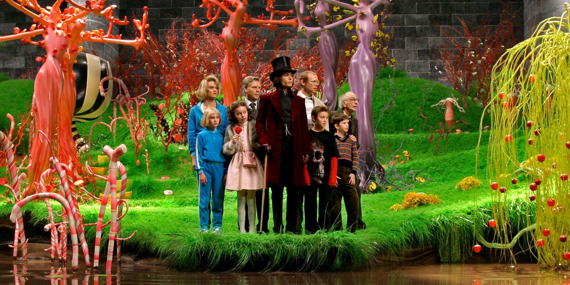 Johnny Depp as Willy Wonka surrounded by the winners and their guardians standing in a room filled with candy in Charlie and the Chocolate Factory.