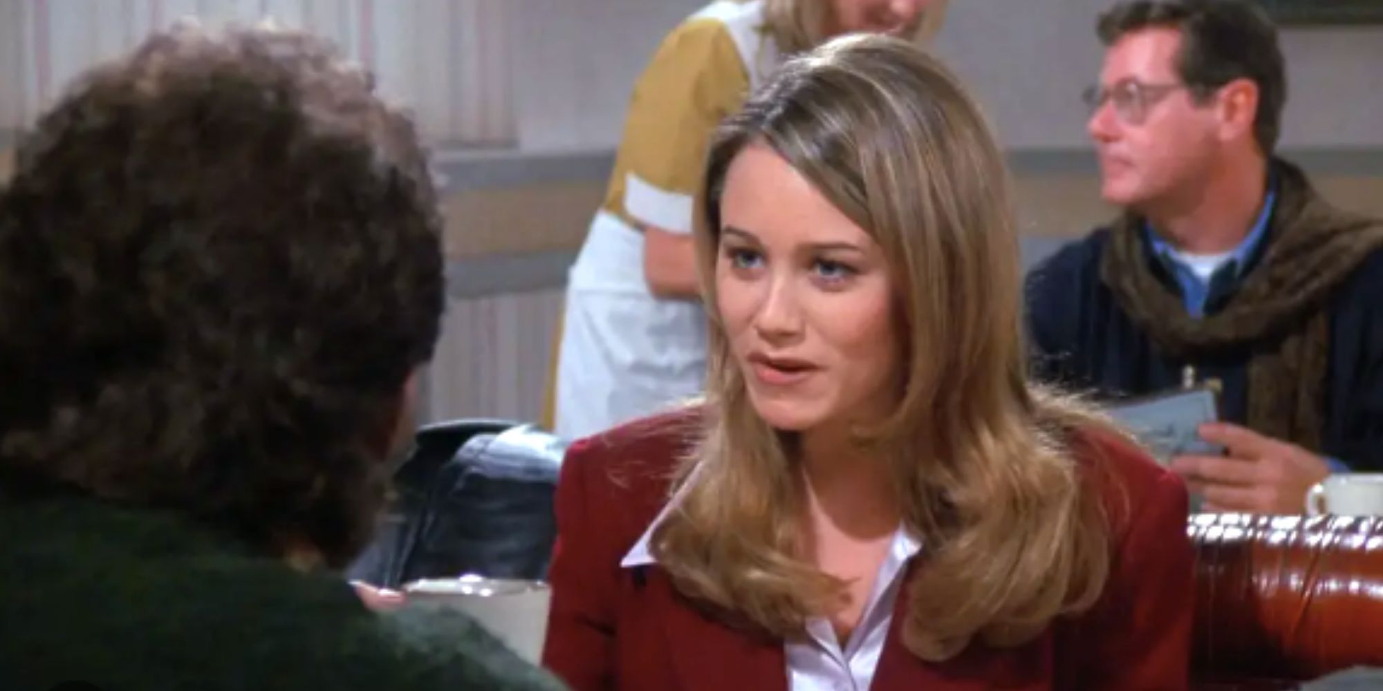Christine Taylor sentou-se em frente a Jerry em uma mesa em Seinfeld