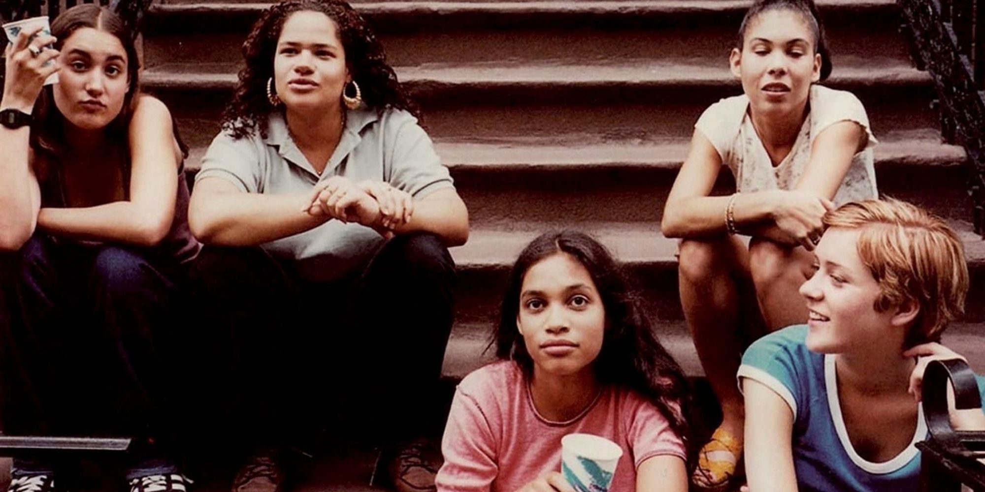 Rosario Dawson and others sit on steps outside in Kids.