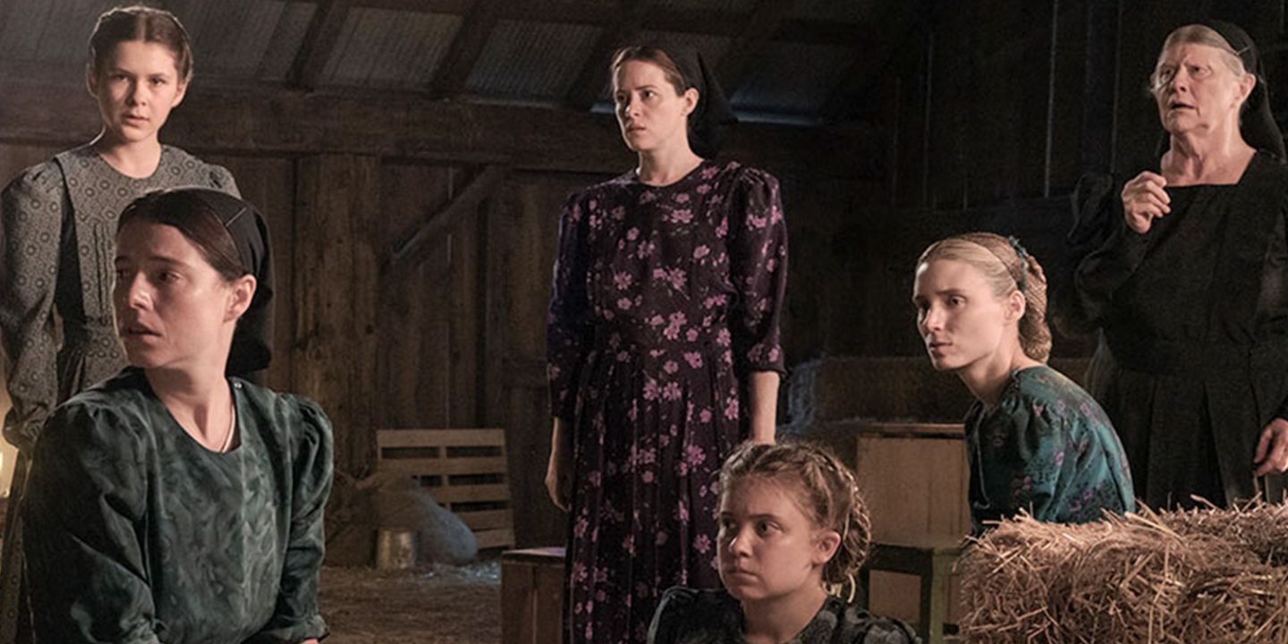 A group of women on a barn looking in the same direction with confused expressions in Women Talking.
