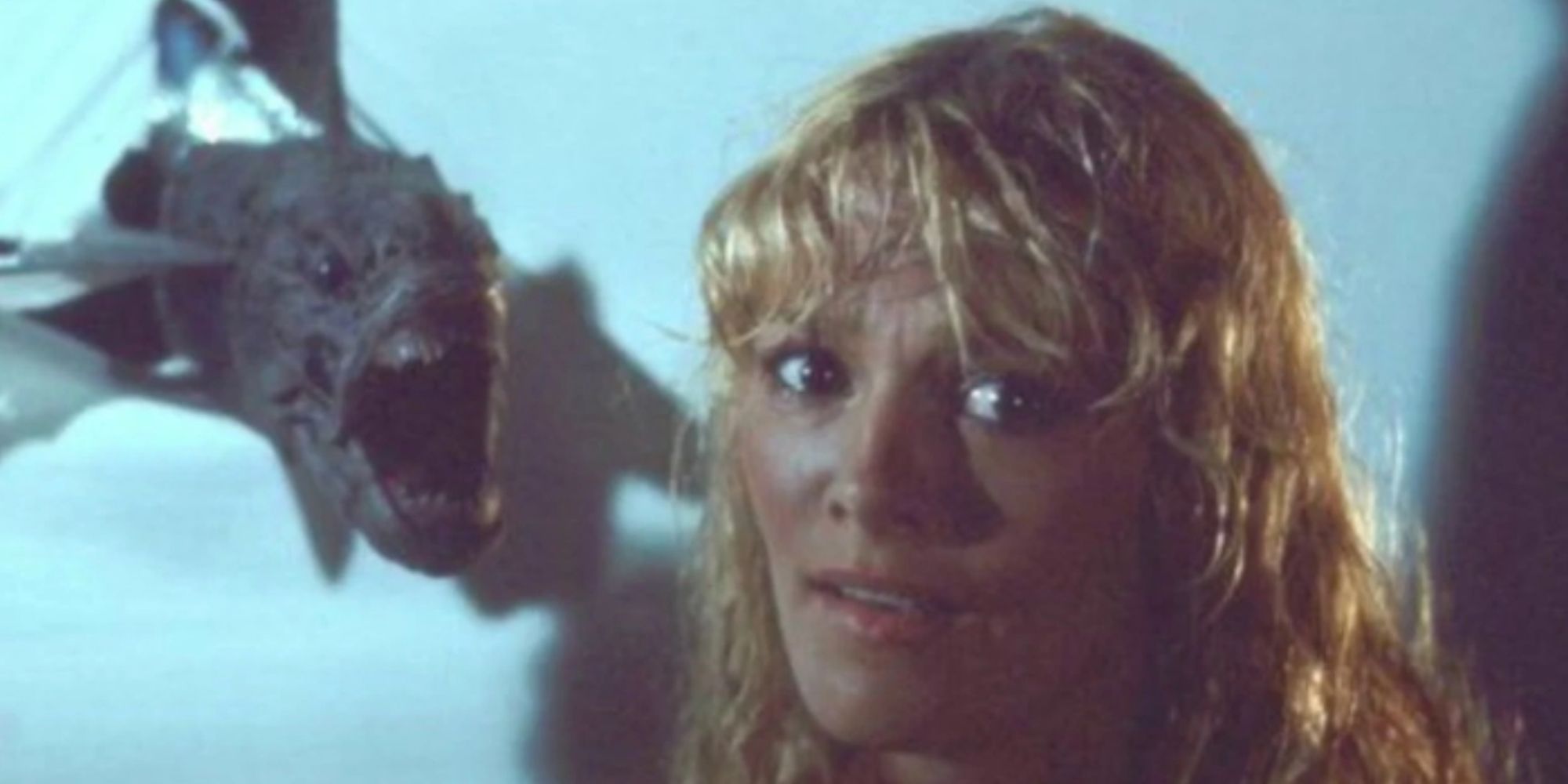 Connie Lynn Haden como Loretta con una piraña volando hacia su cabeza con la boca abierta en Piranha II: The Spawning