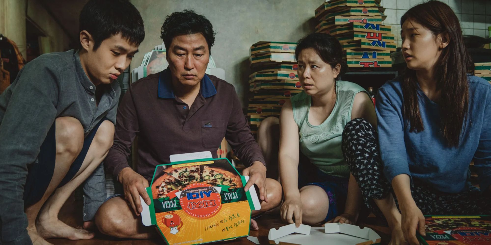 The Kim family (Song Kang-ho, Choi Woo-shik, Park So-dam, and Jang Hye-jin) folding pizza boxes in Parasite