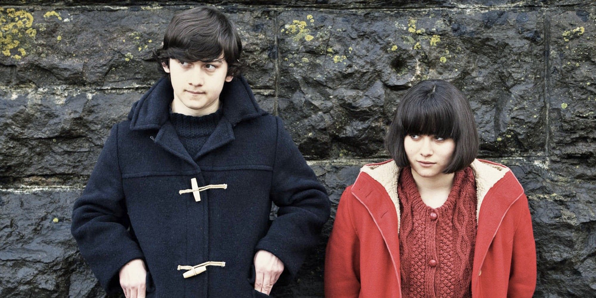 Craig Roberts and Yasmin Paige in 'Submarine' standing in front of a wall.