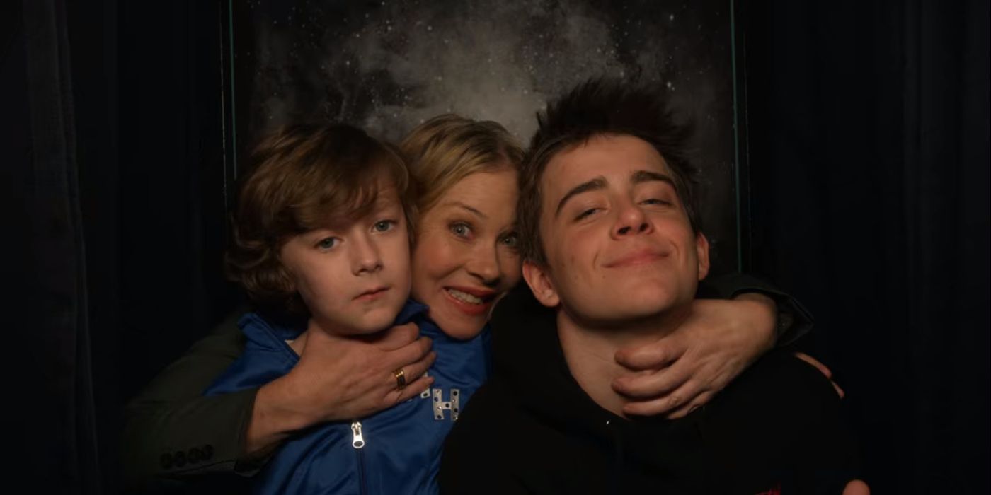 Christina Applegate as Jen Harding in photo booth with Sam McCarthy as Charlie and Luke Roessler as Henry in Netflix's Dead to Me