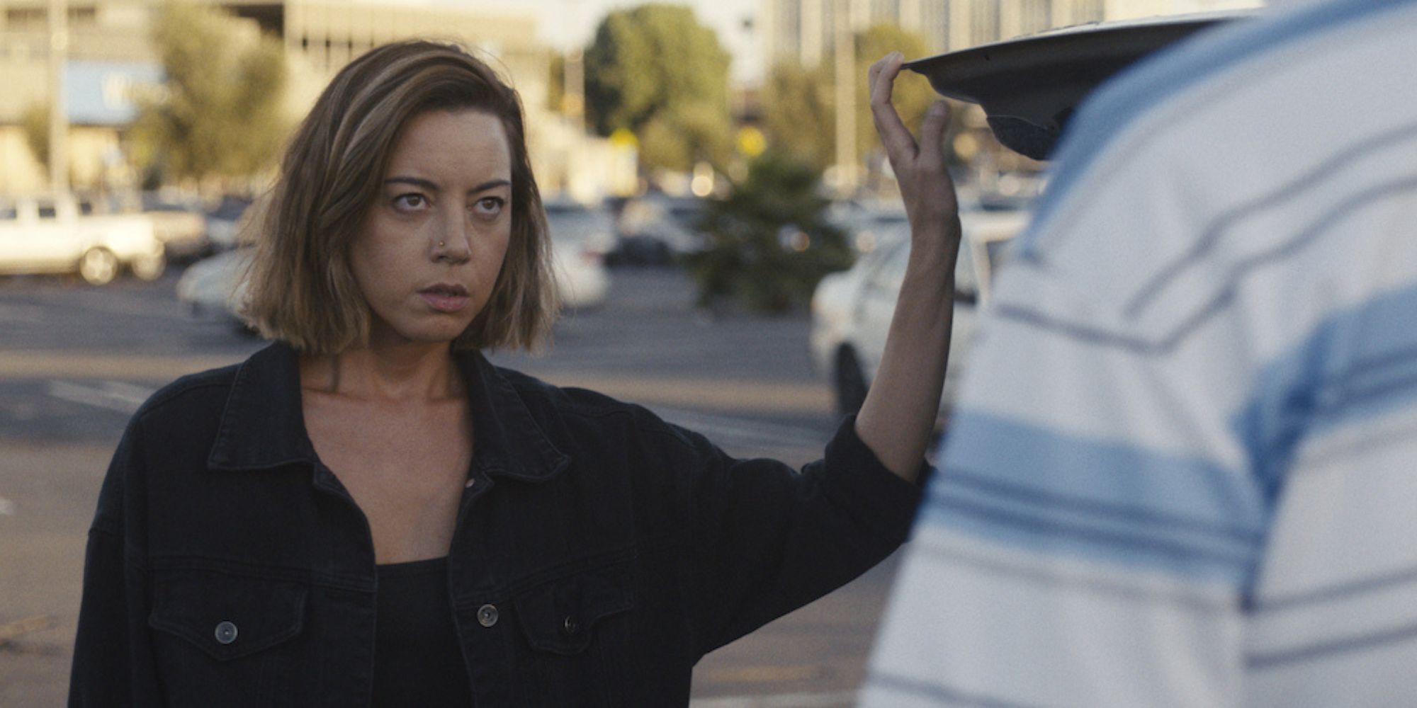 Aubrey Plaza dans le rôle d'Emily dans Emily the Criminal tenant ouvert le coffre de sa voiture lors d'une confrontation.