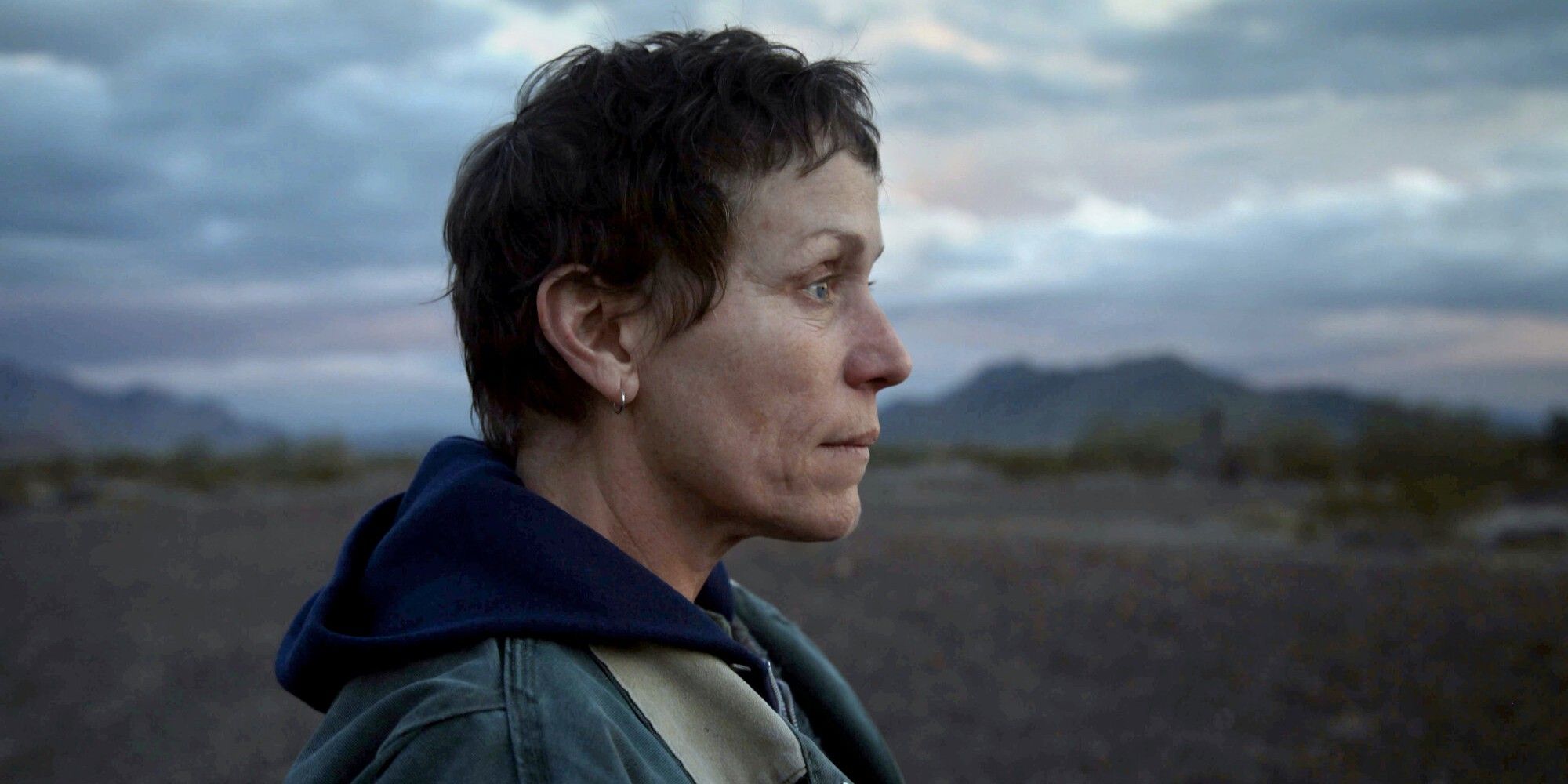 Close up shot of Frances McDormand as Fern, standing in a vast field in 'Nomadland.'