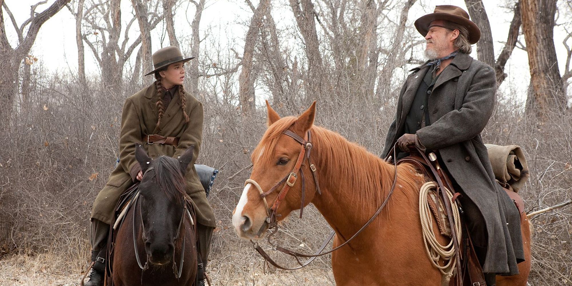 Mattie Ross (Hailee Steinfeld) and Rooster Cogburn (Jeff Bridges) talking while riding horses in True Grit.