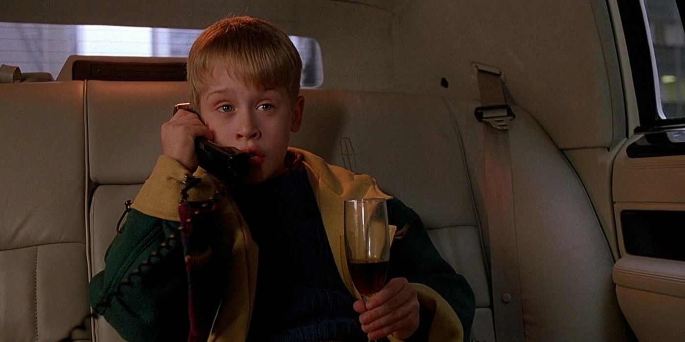 Macaulay Culkin's Kevin McCallister in the back of a limo with a phone in one hand and a glass in his other hand