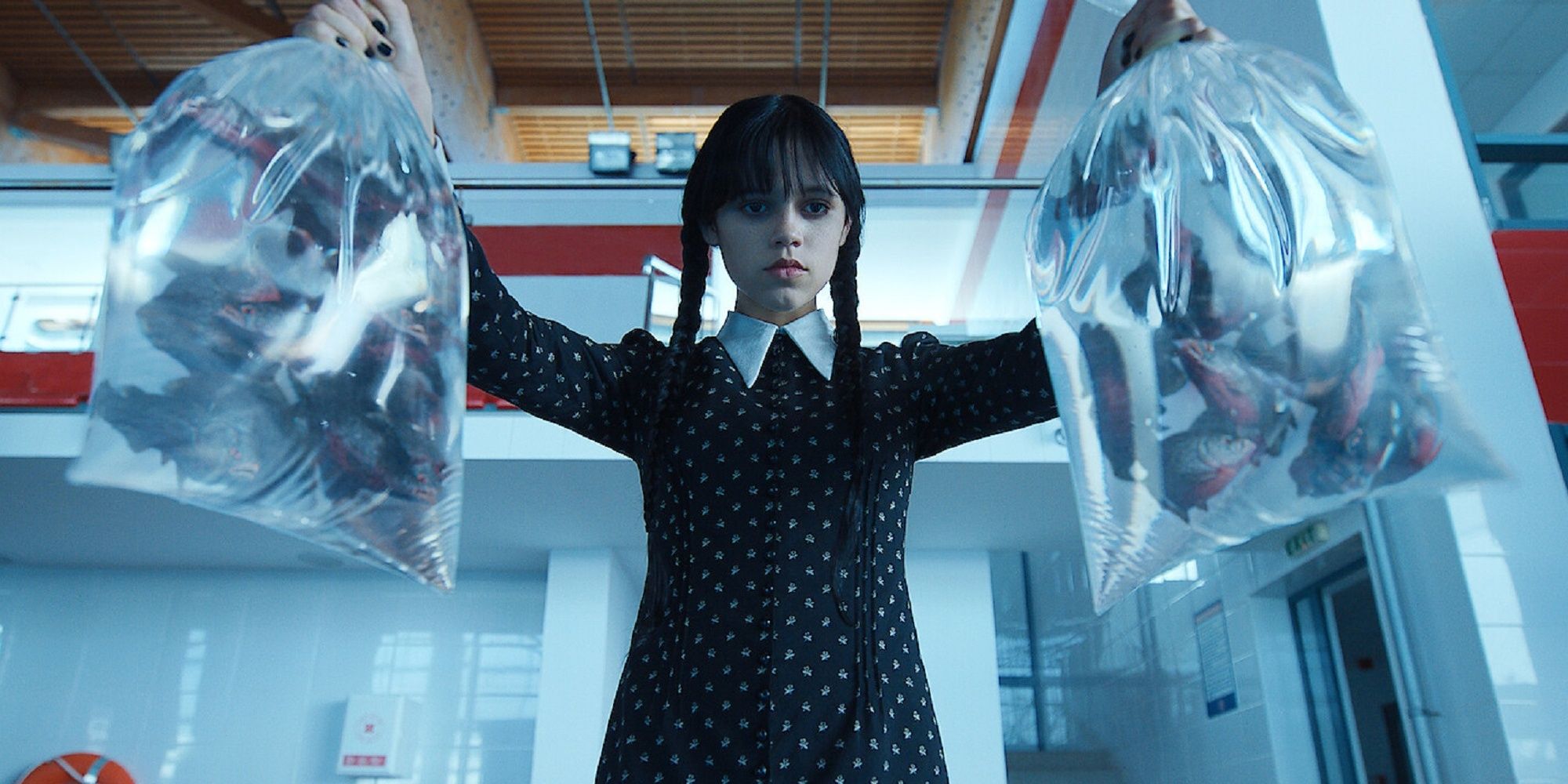 Wednesday Addams holding bags of piranhas at the Nevermore Academy swimming pool.