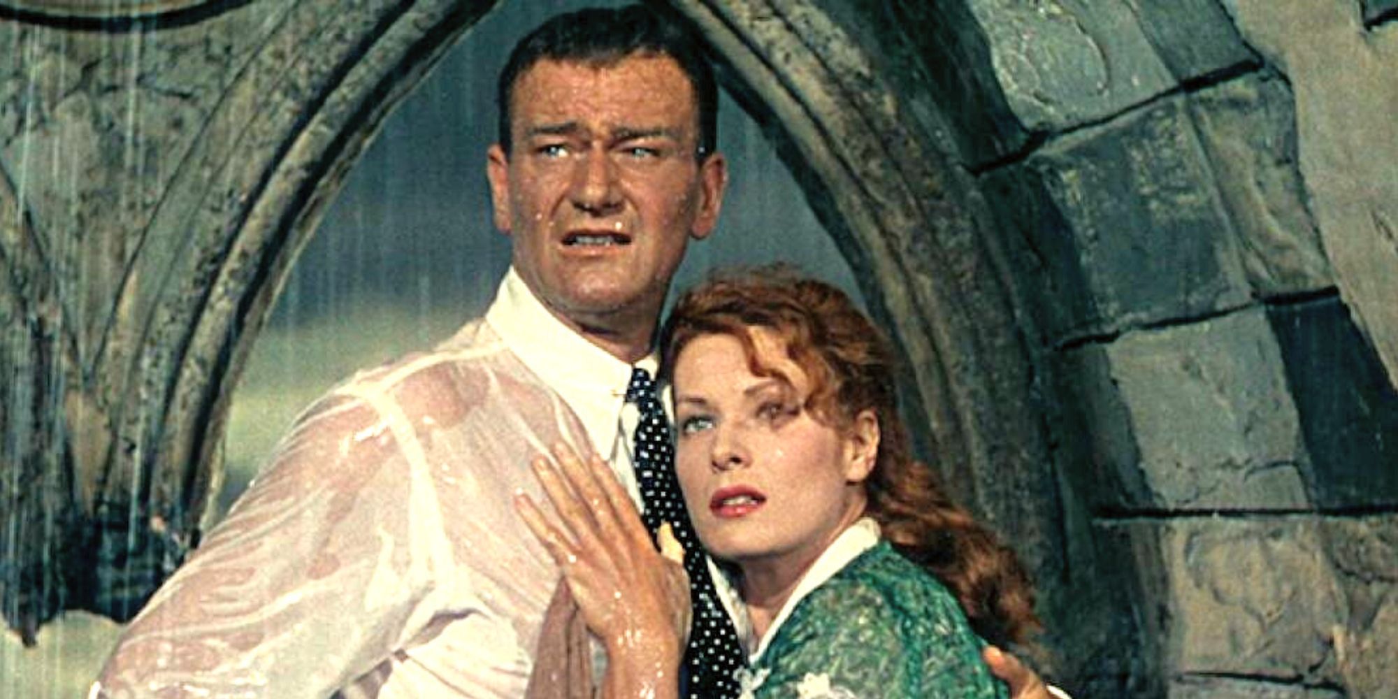 John Wayne and Maureen O'Hara holding each other in the rain in The Quiet Man