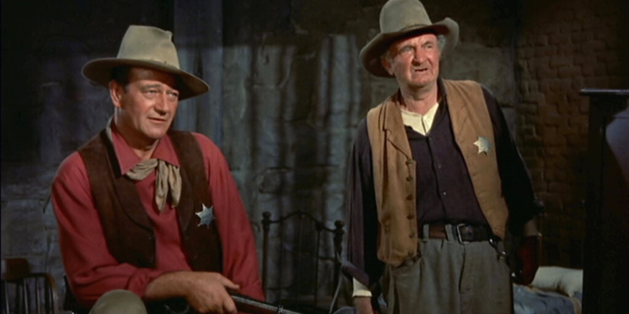 John Wayne sentado e Walter Brennan ao lado dele em Rio Bravo