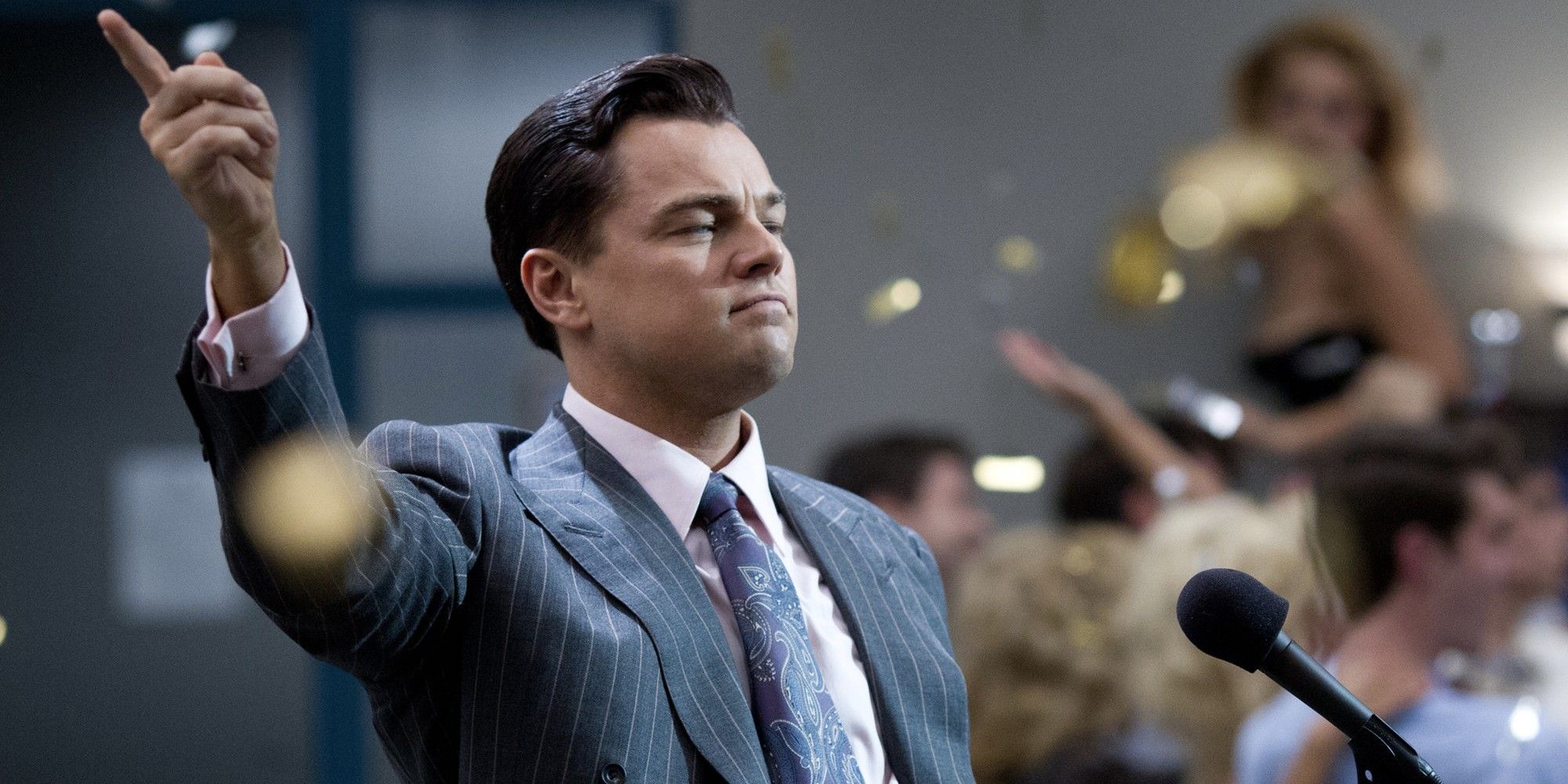 Leonardo DiCaprio as Jordan Belfort, standing amid a celebration at his office while confetti falls around him in The Wolf of Wall Street