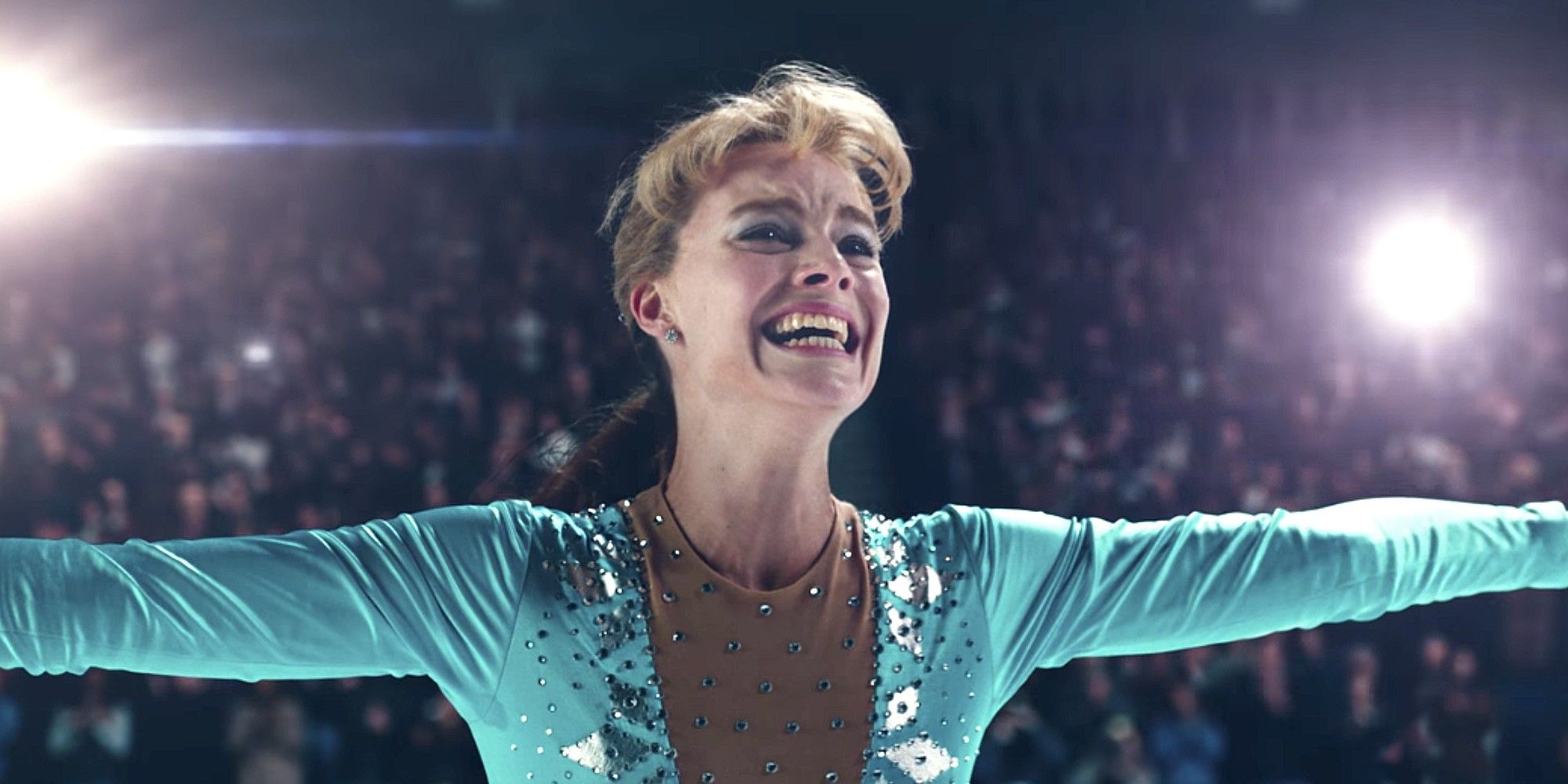 Margot Robbie as Tonya Harding smiling and spreadin her arms while skating in 'I, Tonya'.