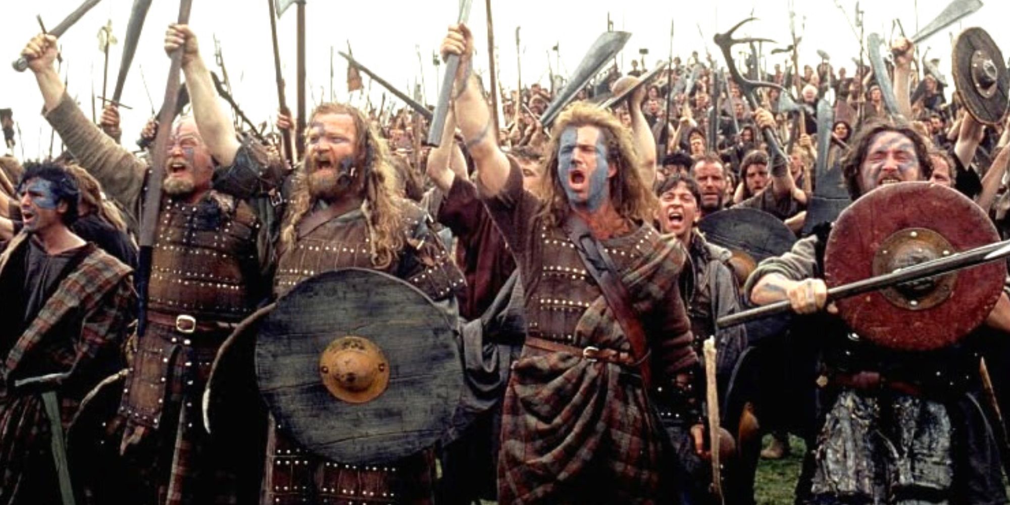 Mel Gibson standing with a large group of men cheering before going to fight in Braveheart