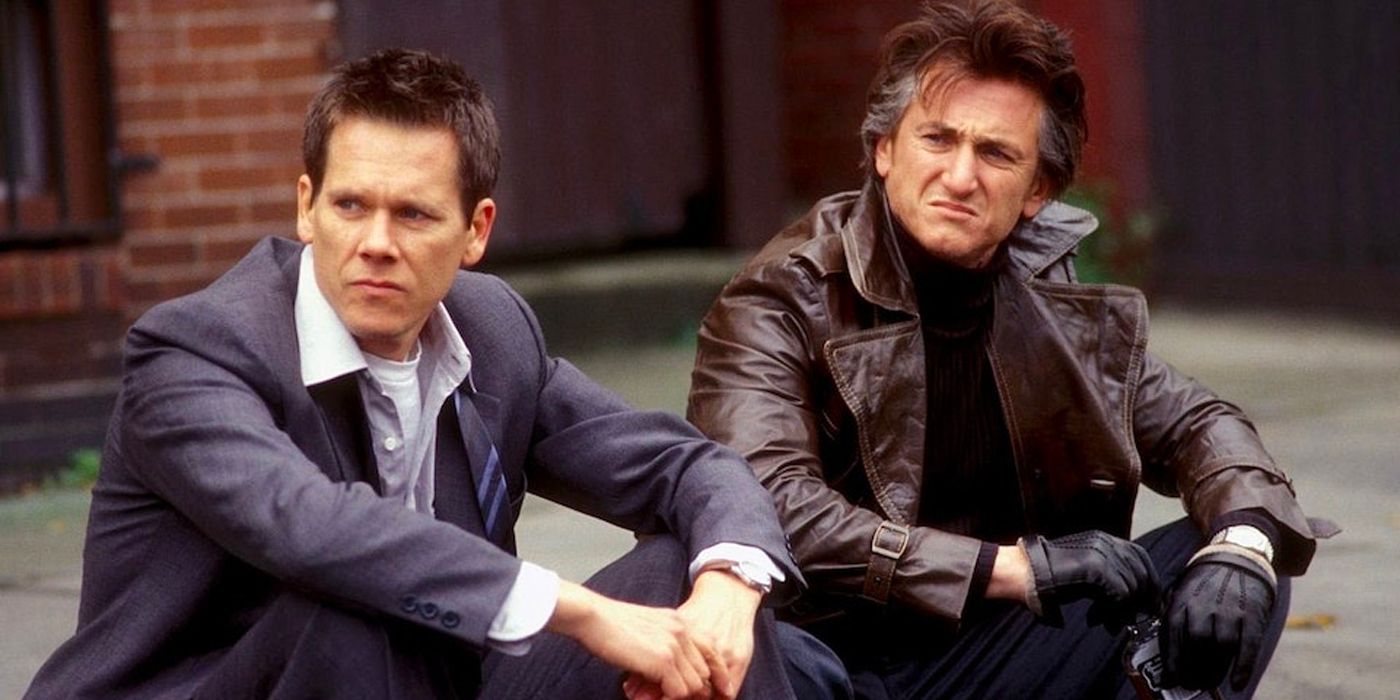 Kevin Bacon and Sean Penn sitting next to each other on a curb in Mystic River