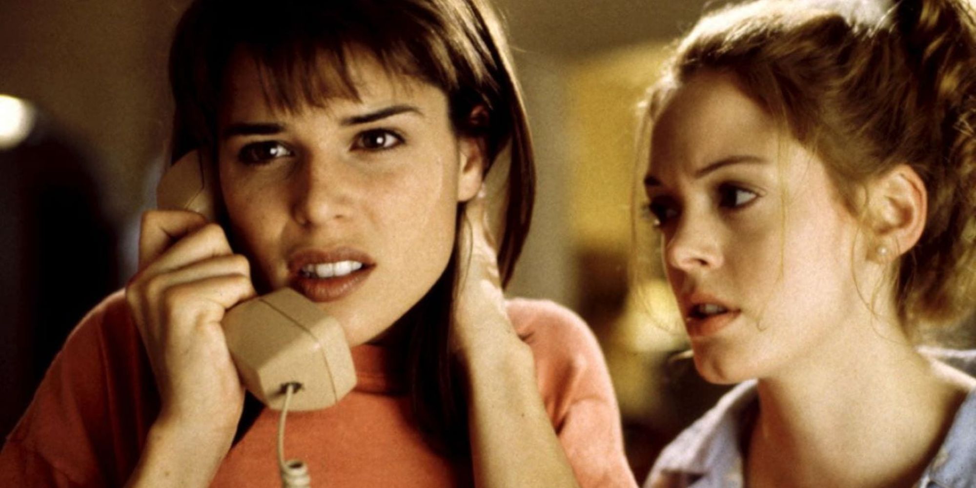 Neve Campbell au téléphone avec Rose McGowan à ses côtés dans Scream.