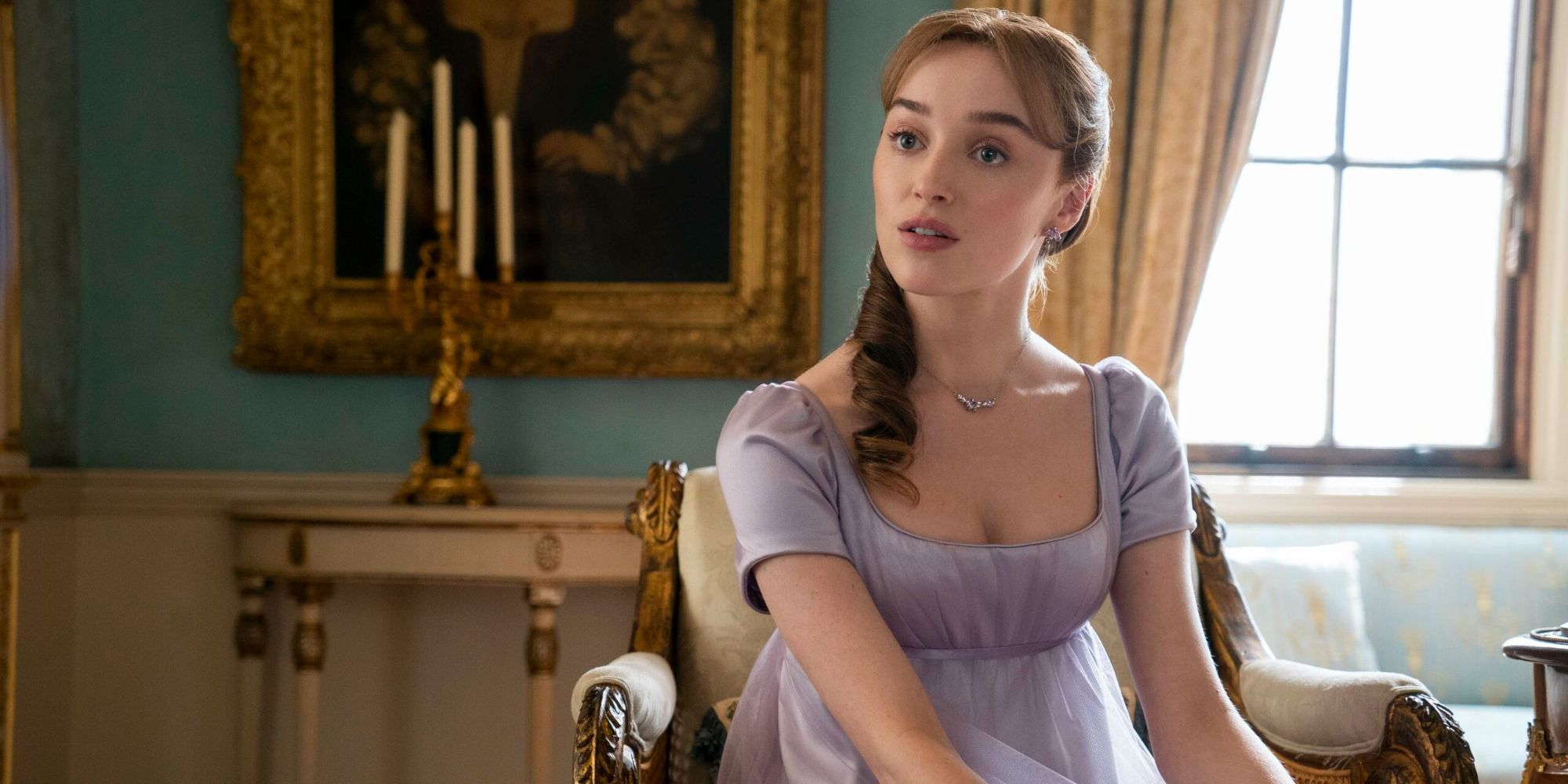 Phoebe Dynevor as Daphne sitting on a chair and looking at someone off-camera in Bridgerton
