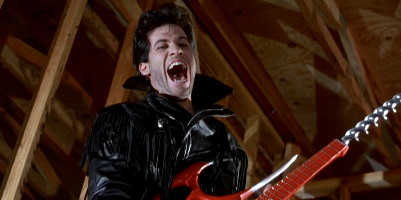 A young man screams in excitement while holding a guitar in Slumber Party Massacre 2