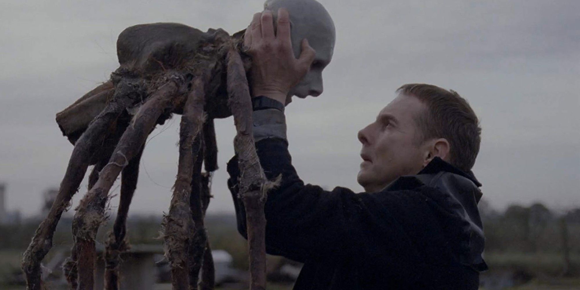 Sean Harris holding a bizarre humanoid creature with spider legs in 'Possum'