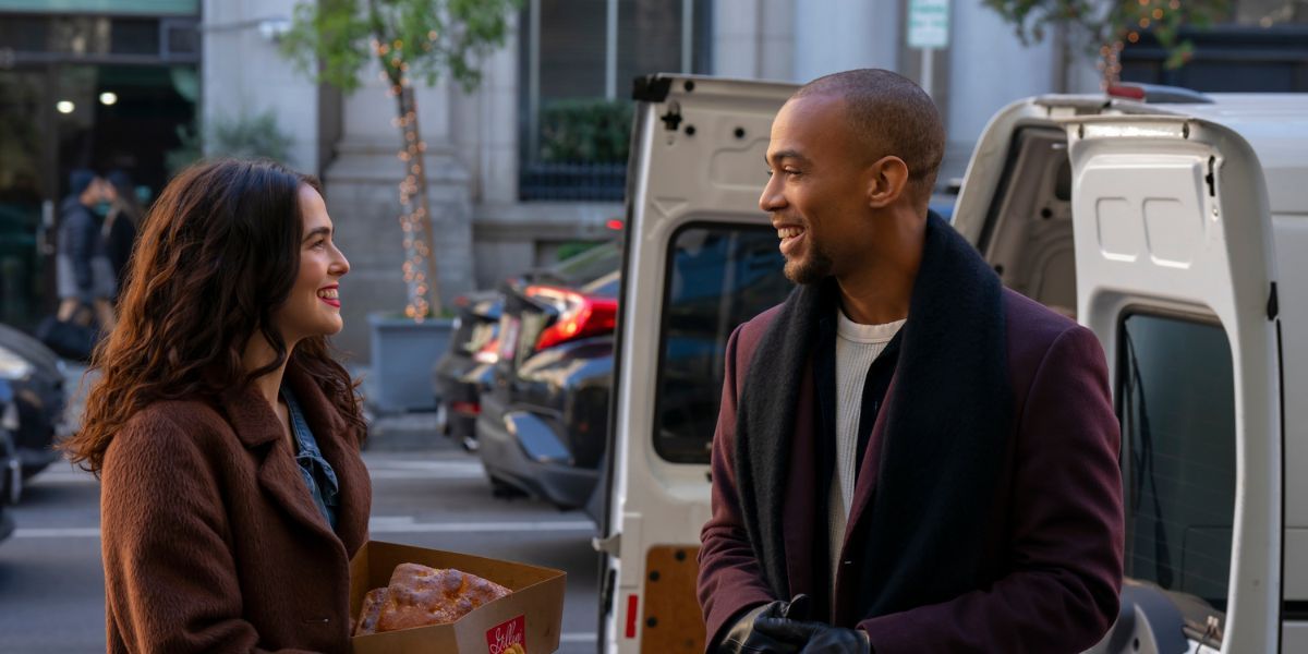 Zoey Deutch and Kendrick Sampson smiling at each other beside a white van.