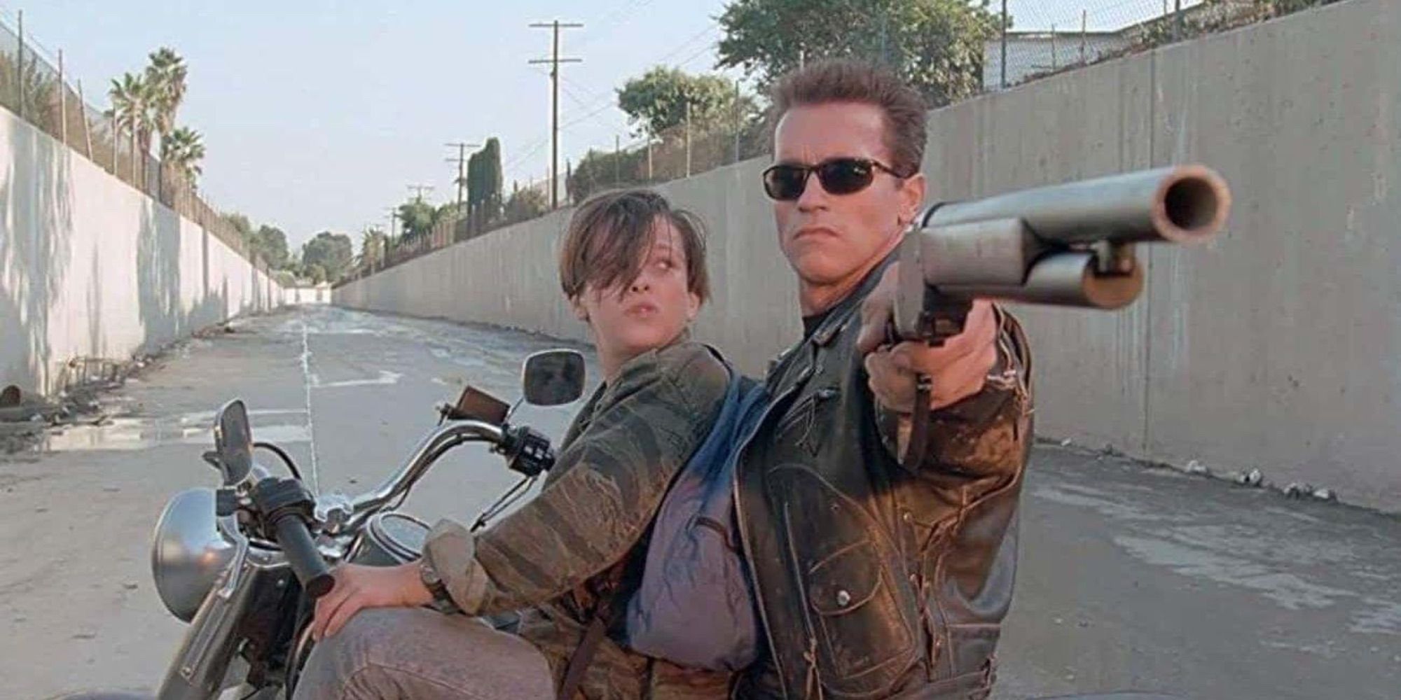 Edward Furlong como John Connor em uma motocicleta com Arnold Schwarzenegger como o Exterminador do Futuro mirando uma espingarda