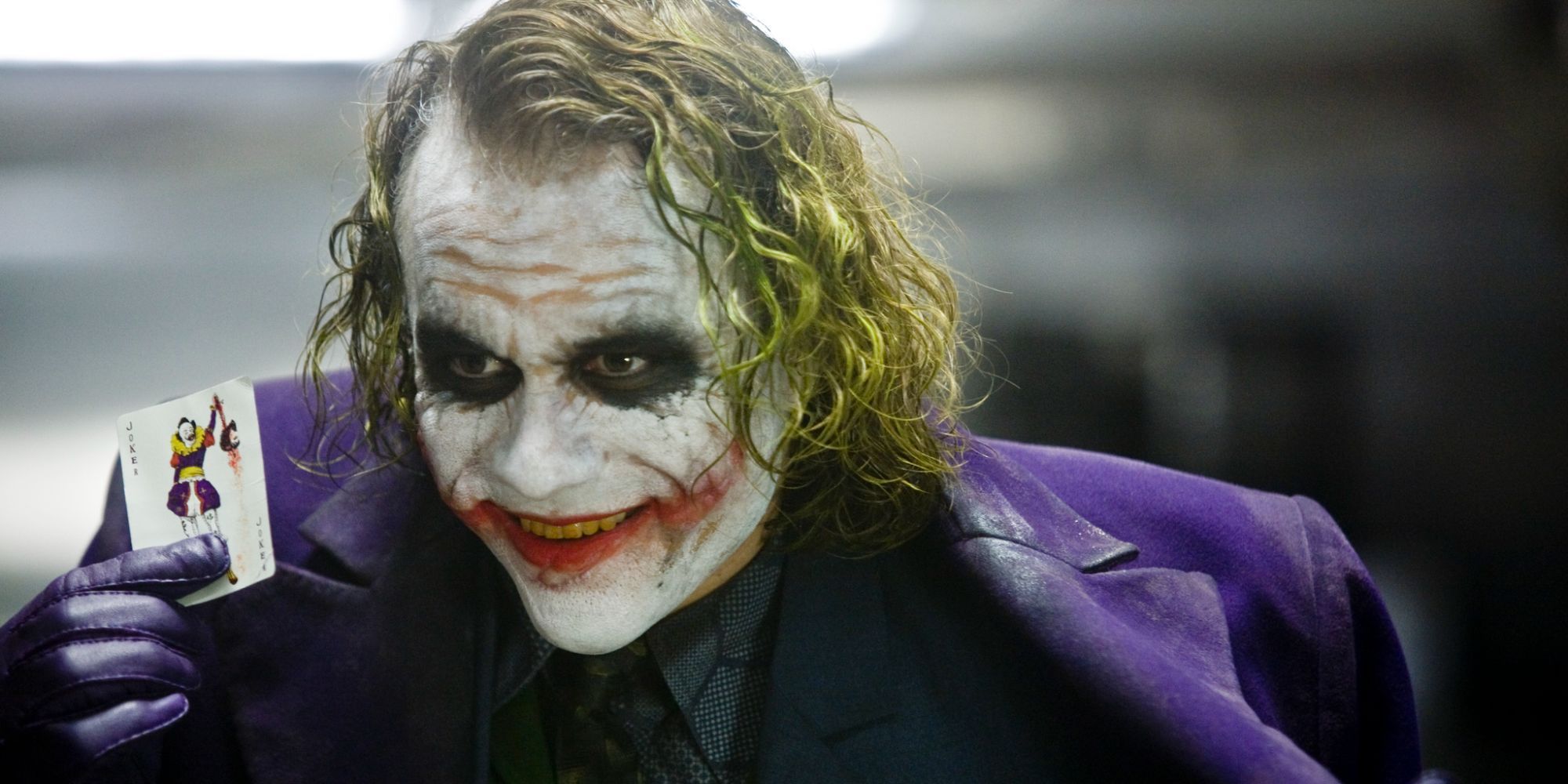 Joker smiling while showing off his card in The Dark Knight.