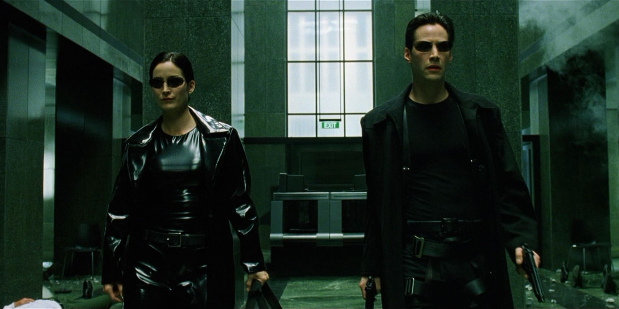 Carrie-Anne Moss como Trinity y Keanu Reeves como Neo marchan a través de un edificio listo para la batalla.