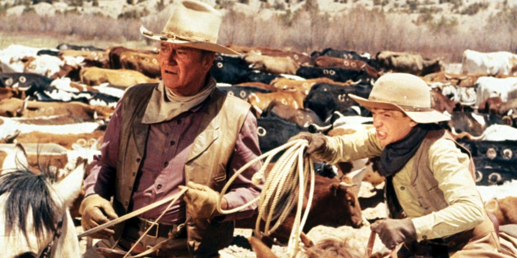 John Wayne as Wil Andersen riding a horse in 'The Cowboys.'