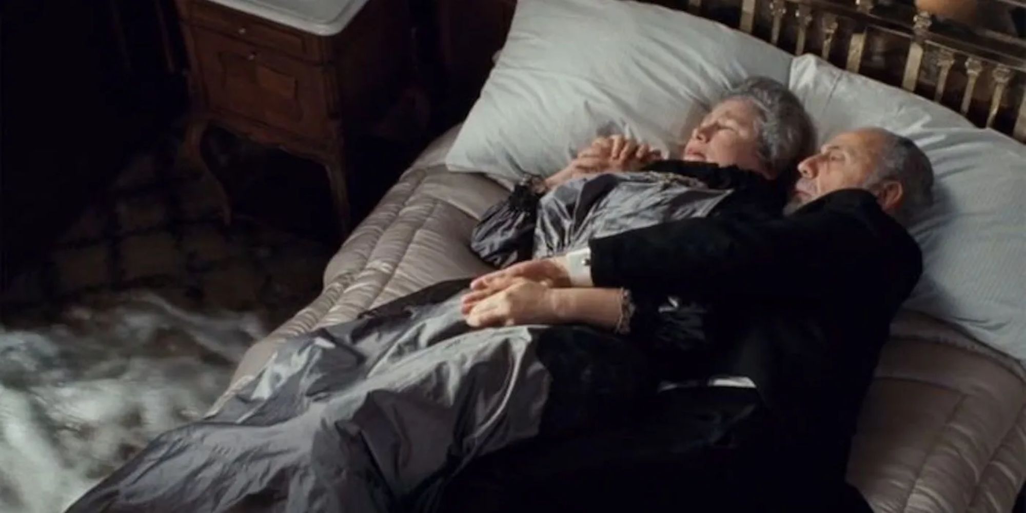 Isador e Ida Strauss se abraçam em sua cama enquanto a água corre para dentro de sua cabana