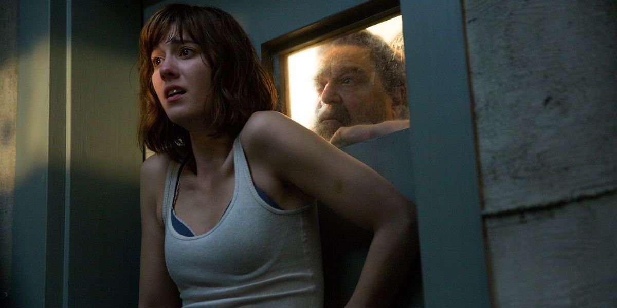 Mary Elizabeth Winstead as Michelle pressed against a door while a man looks through a small window in 10 Cloverfield Lane.