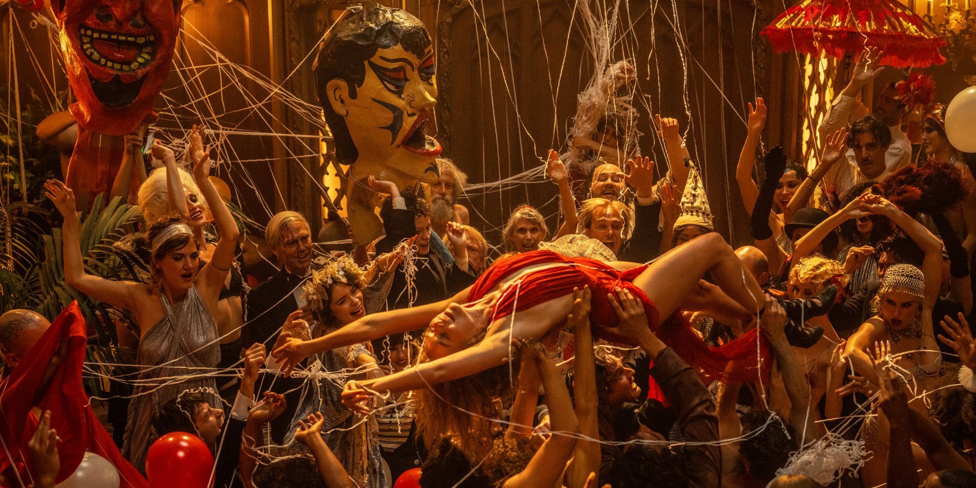 Margot Robbie as Nellie LaRoy being lifted by a crowd at a party in Babylon
