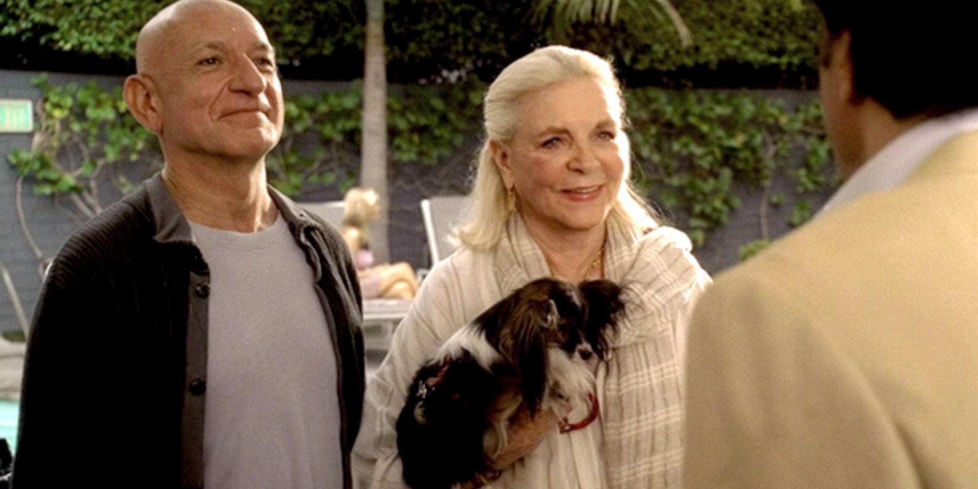 Ben Kingsley standing next to Lauren Bacall who is holding a dog both looking at someone who has their back to the camera in The Sopranos