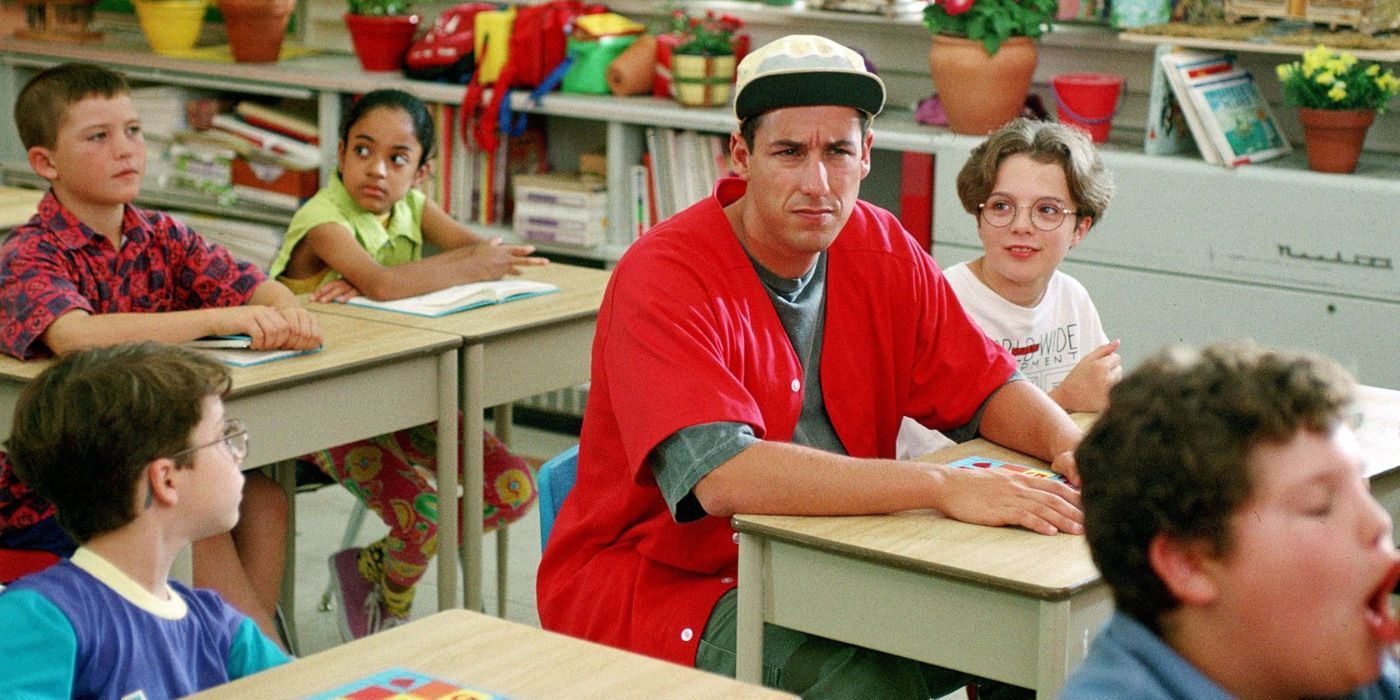 Adam Sandler as Billy Madison sitting at a desk in a classroom filled with children in 'Billy Madison.'