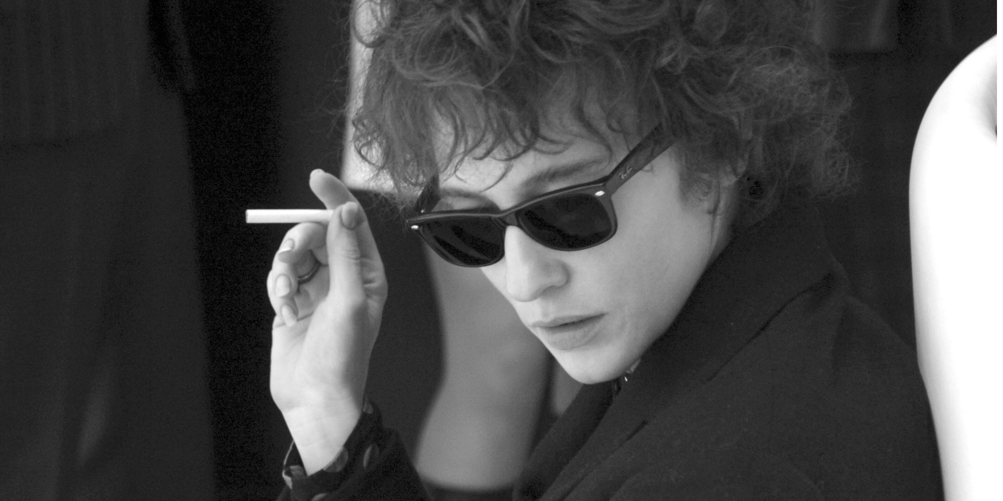 Boby Dylan holding a cigarrette and looking down in I'm Not There.