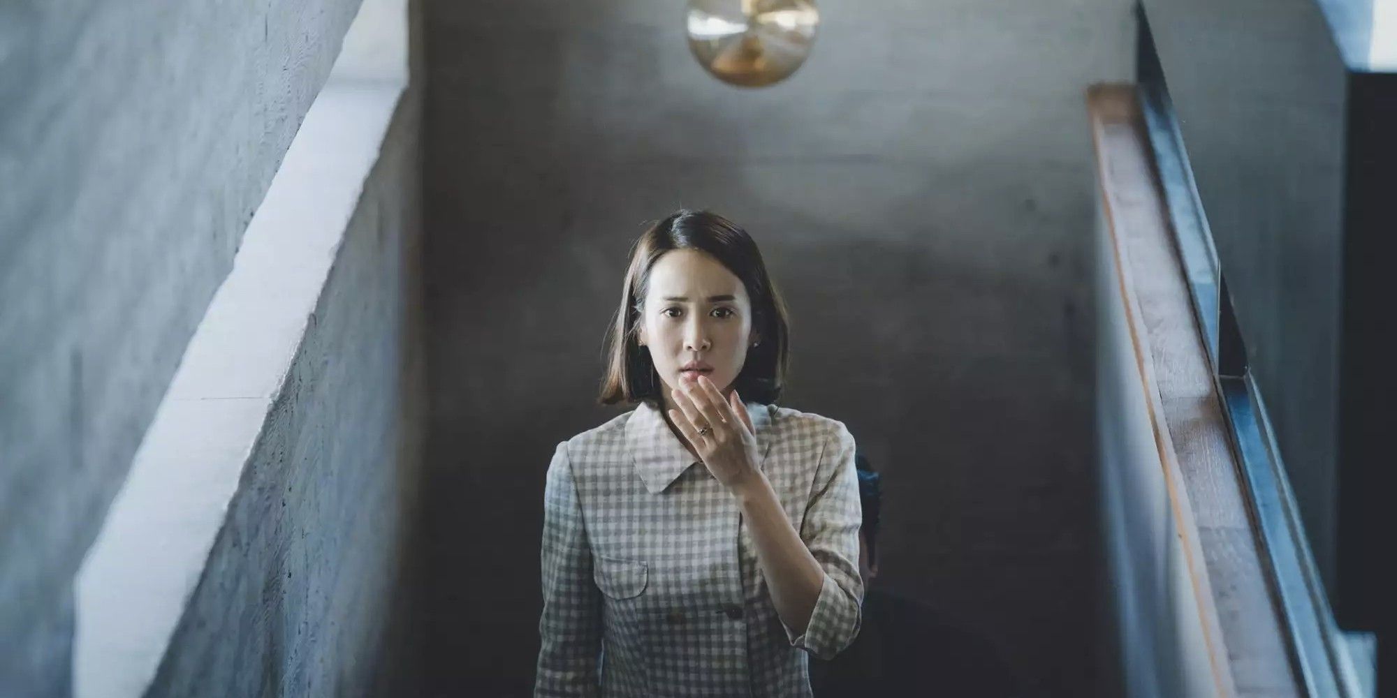 Cho Yeo-jeong as Choi Yeon-gyo, walking up a staircase with her hand to her mouth in surprise in 'Parasite'