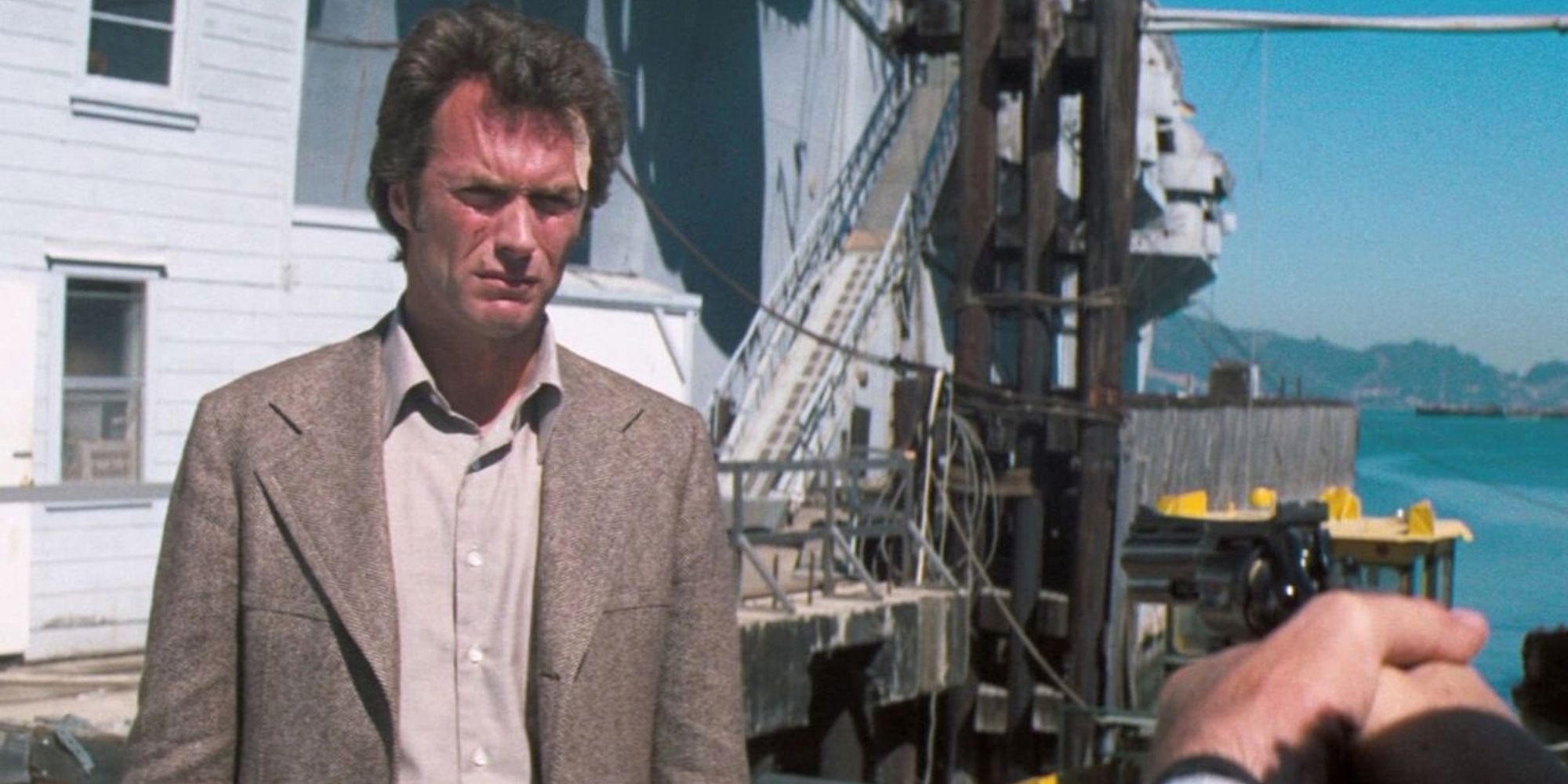 Clint Eastwood, debout sur un port de plaisance, regarde quelqu'un hors champ dans Magnum Force.