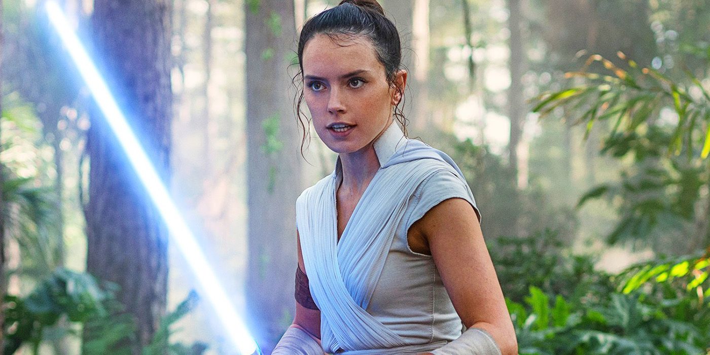 Daisy Ridley as Rey holding a lightsaber in the woods in The Rise of Skywalker