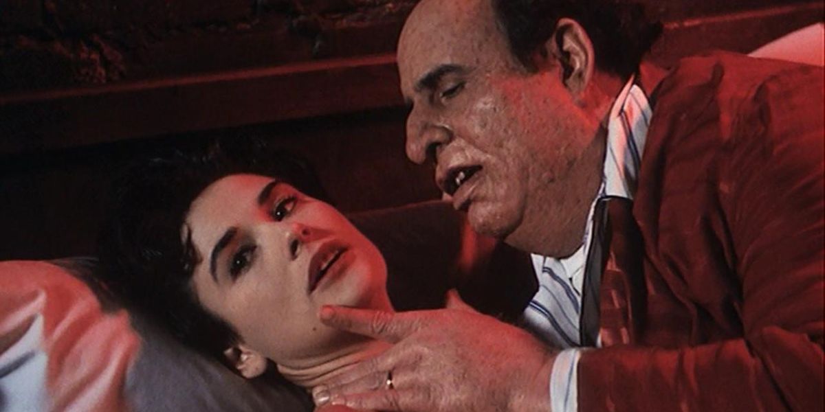 Cathy, played by Demi Moore, looking afraid as her husband Charlie, played by Jeffrey Tambor, looms over her with his hand on her neck in Tales From the Crypt episode "Dead Right."