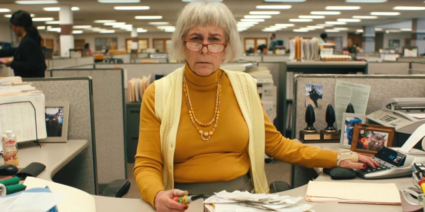 Jamie Lee Curtis as Deirdre sitting at her desk in Everything Everywhere All at Once