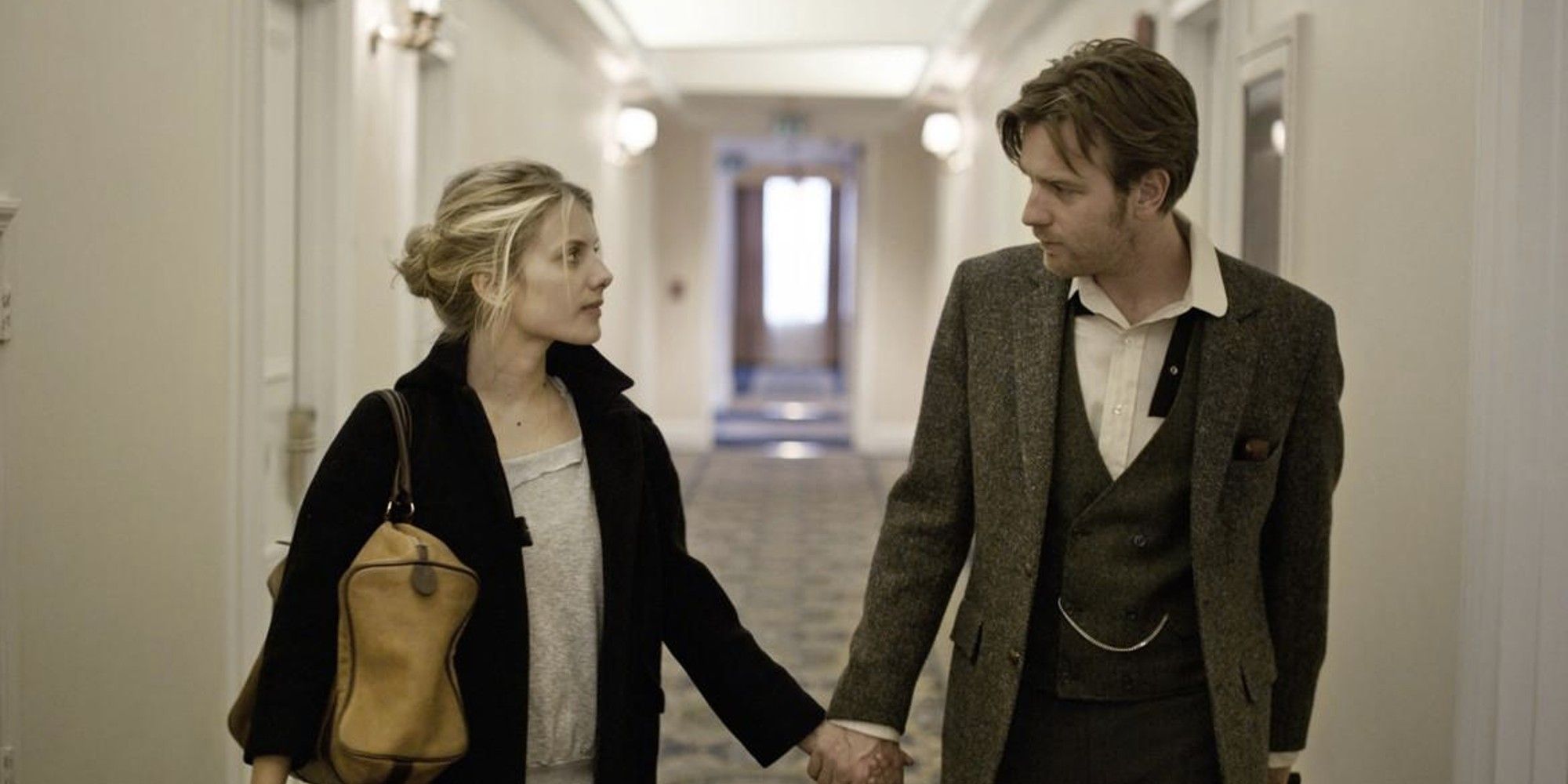 Ewan McGregor y Melanie Laurent se toman de la mano y se miran fijamente en Principiantes.