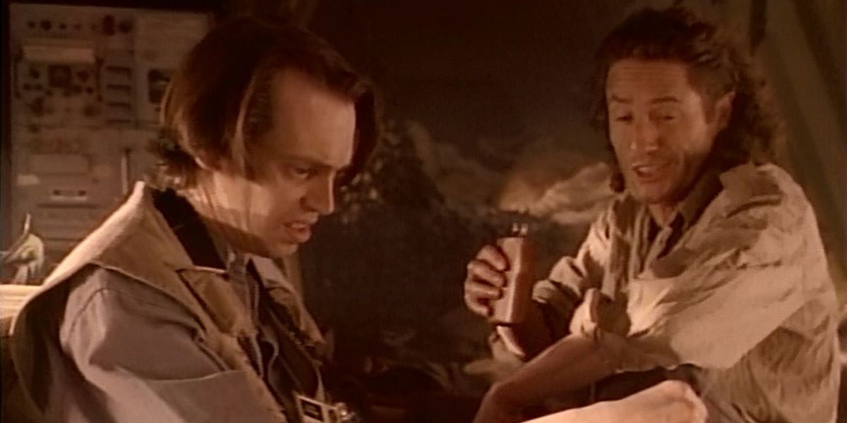 Photographers Isaac (Steve Buscemi) and Dalton (Roger Daltrey) sitting and looking at something together in Tales from the Crypt episode "Forever Ambergris."