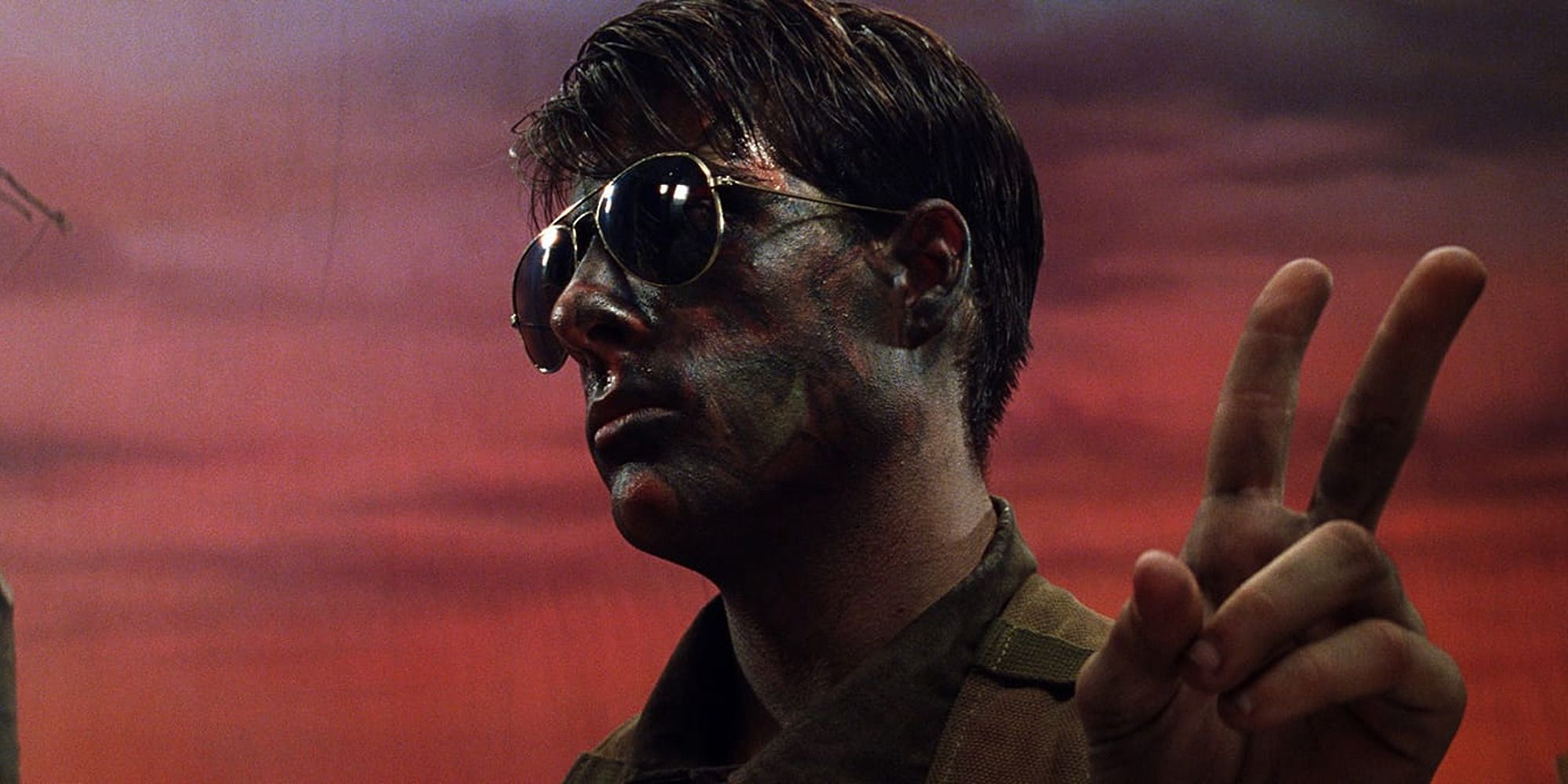 homem com óculos escuros e pintura de guerra no rosto, faz sinal de paz