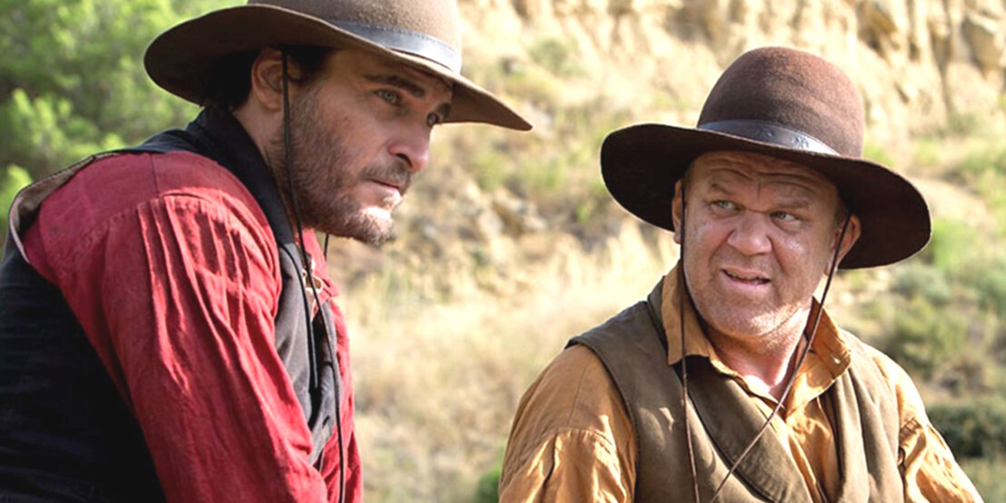 Joaquin Phoenix looking up ahead next to John C. Reilly who is looking at him in The Sisters Brothers