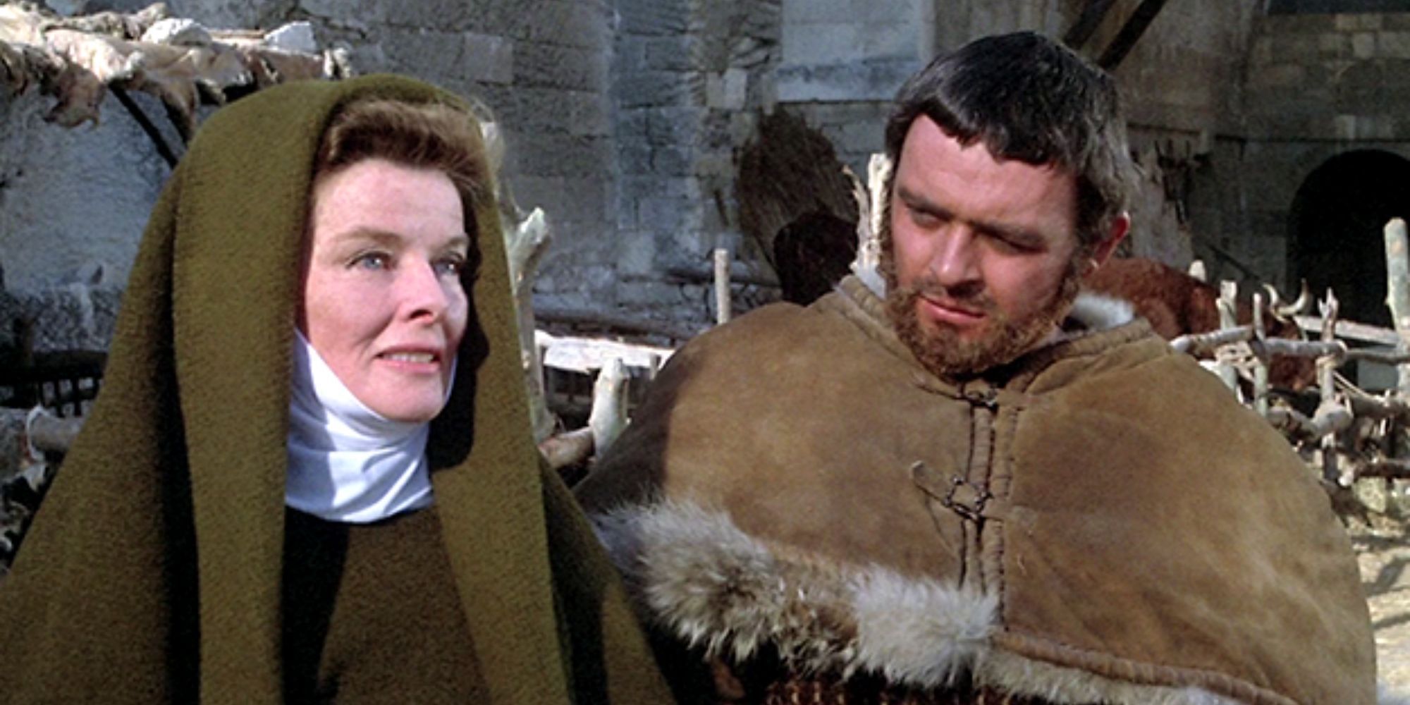 Katharine Hepburn standing next to Anthony Hopkins talking as he looks at her in The Lion in Winter