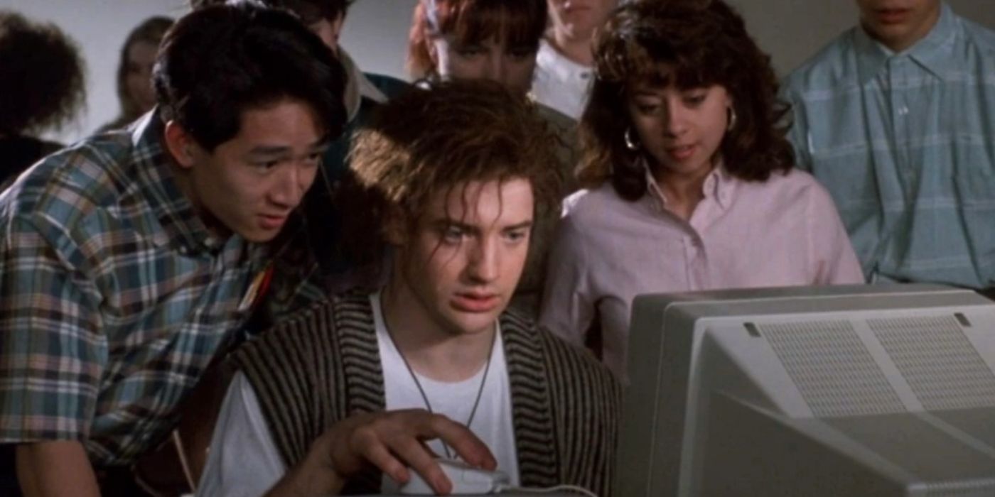 Brendan Fraser in 'Encino Man' sitting in front of a computer monitor looking puzzled as others look on.