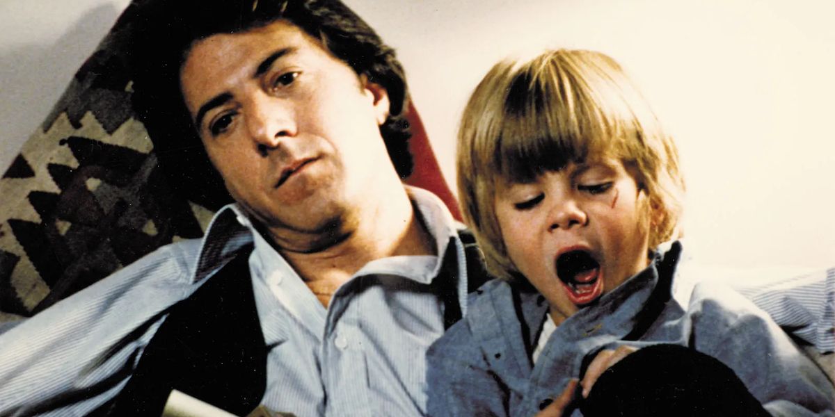 Ted Kramer (Dustin Hoffman) looking bored while Billy Kramer (Justin Henry) yawns in his lap in Kramer vs. Kramer