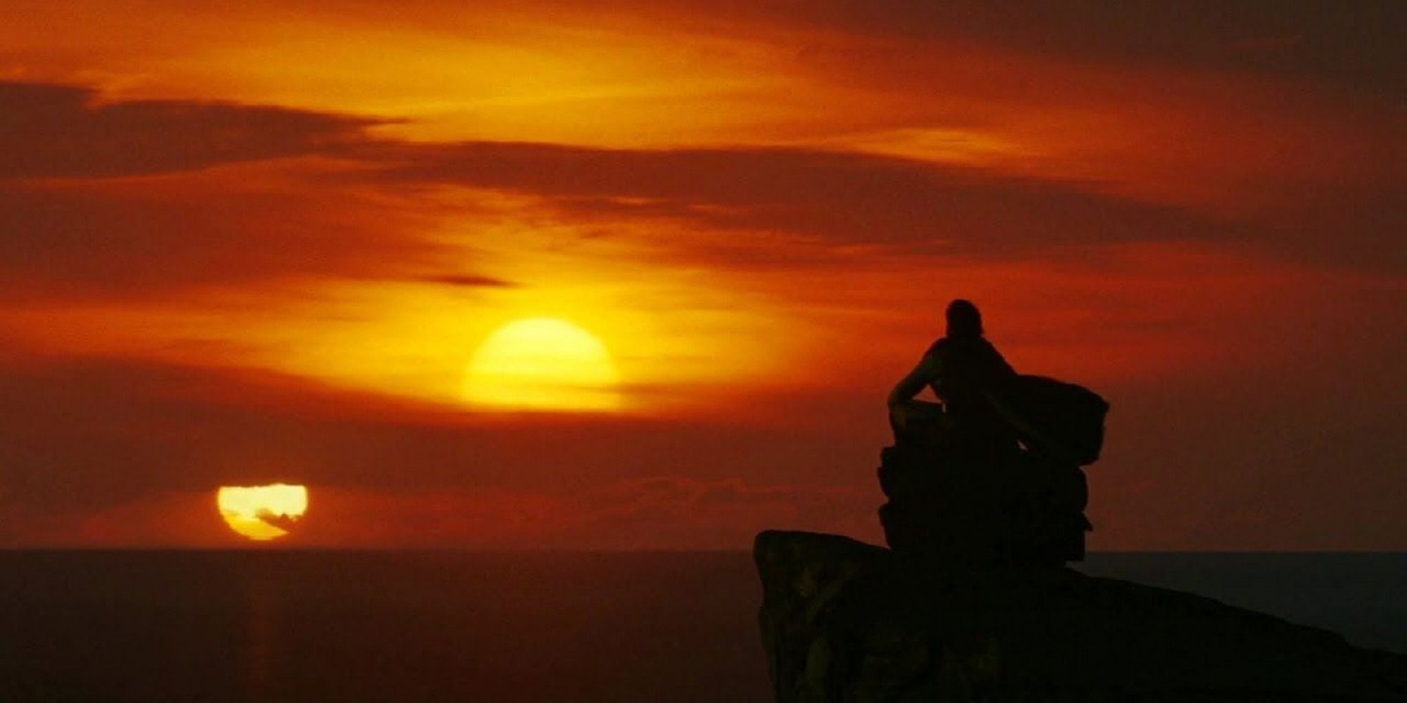 Homme assis sur une falaise regardant les soleils jumeaux.